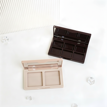 Nude pink and black palette cases open on acrylic podium showing 2-pan and 6-pan interiors