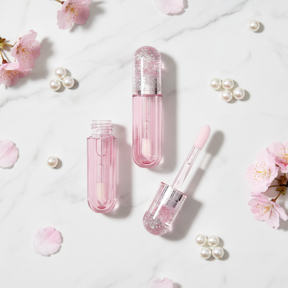 Pink glitter heart lip gloss tubes flat lay on marble with cherry blossoms