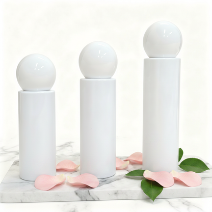 Three white ball cap pump bottles on marble with rose petals